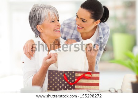 excited middle aged mother looking at her gift from her daughter