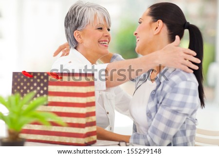 cheerful senior woman receiving a gift from adult daughter