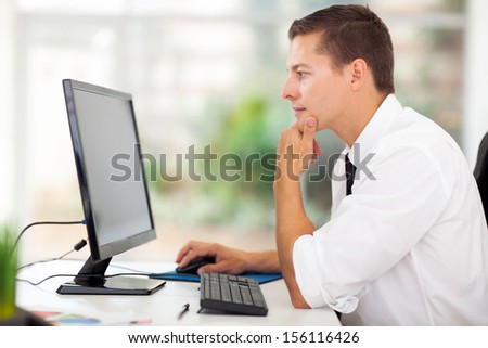 thoughtful young businessman looking at computer screen