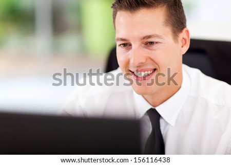 handsome businessman looking at computer screen at workplace