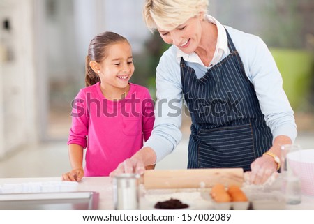loving grandma baking cookies for granddaughter at home