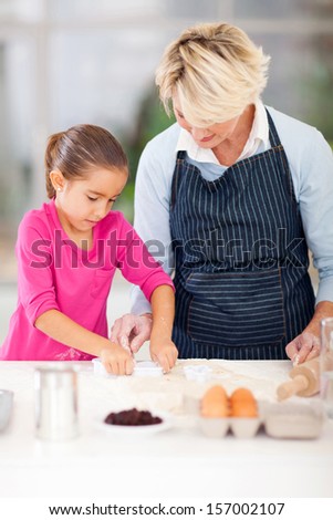 granddaughter and grandmother baking cookies together in kitchen