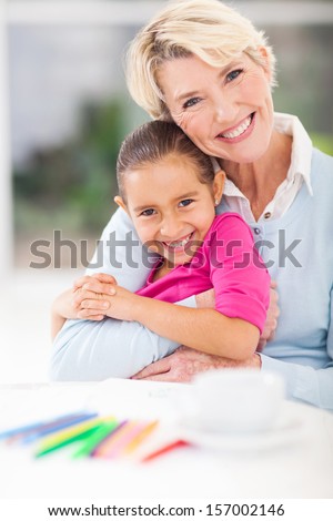 happy senior grandmother hugging her granddaughter at home