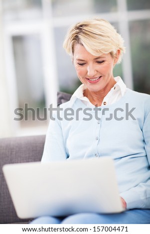elegant middle aged woman using laptop computer at home