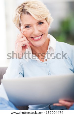attractive middle aged woman with laptop computer and looking at the camera