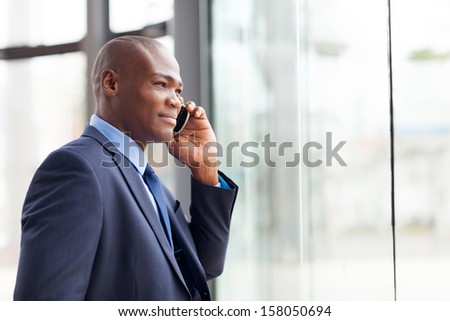 handsome african american businessman talking on mobile phone in modern office