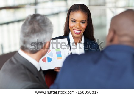 beautiful young african businesswoman explaining graph to business team
