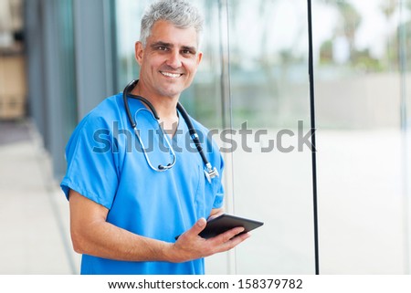 happy male medical doctor using tablet computer in hospital