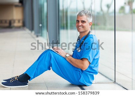 senior medical worker sitting on hospital floor and using laptop computer