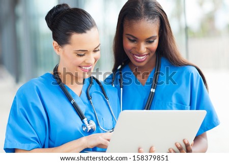 Two Cheerful Female Medical Workers Using Laptop Computer At Hospital