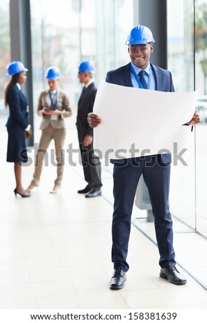 handsome afro american architect standing in office with co-worker on background