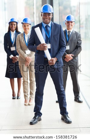 happy african american architect standing in front of colleagues in modern office