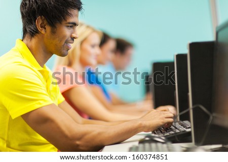 male university student in computer lab with classmates on background