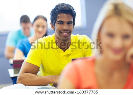 handsome male indian college student in lecture room with classmates