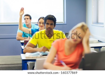 pretty college student raising her hand in lecture room