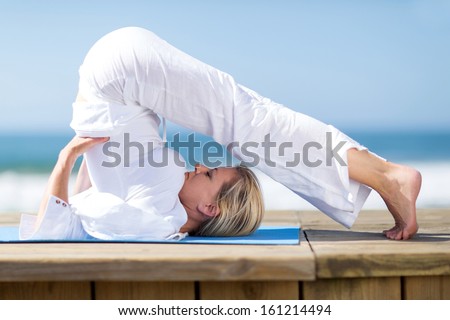 flexible mature woman yoga by the beach