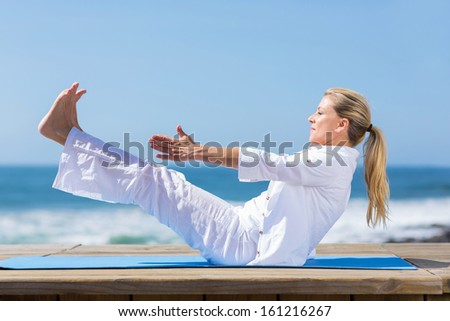 heathy mid age woman yoga exercise on beach