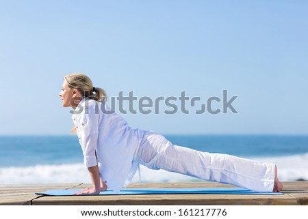 fit mid age woman yoga pose on beach