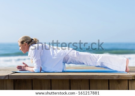 beautiful mid age woman yoga on beach