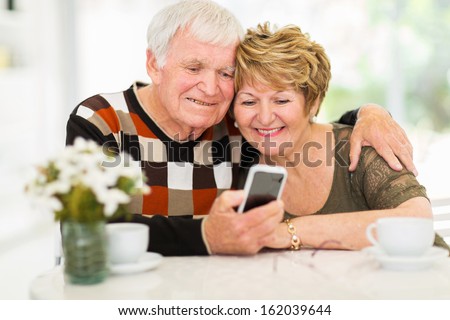 lovely elderly couple using smart phone at home