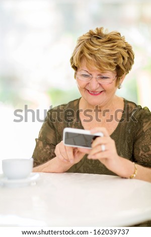 happy elderly woman reading emails on smart phone at home