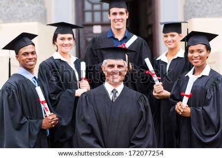 dean standing with group of happy graduates outside university