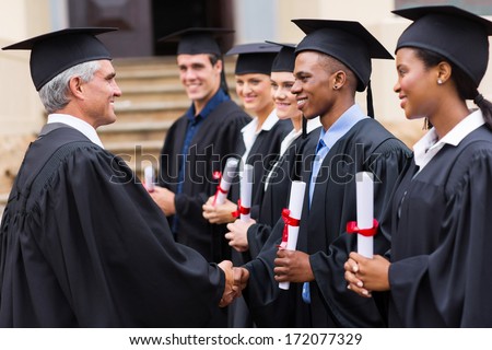 senior university professor handshaking with young graduates