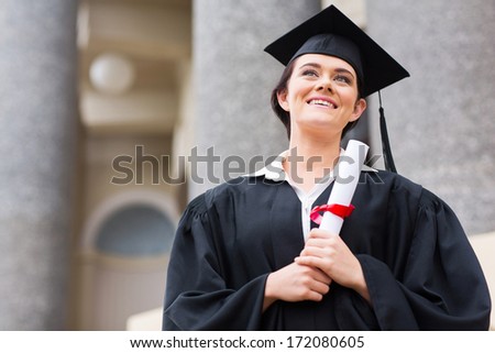 college student in graduation cap and gown in front of school building