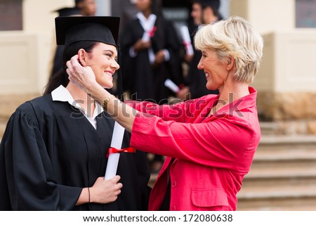 happy middle aged mother hugging her daughter at graduation ceremony