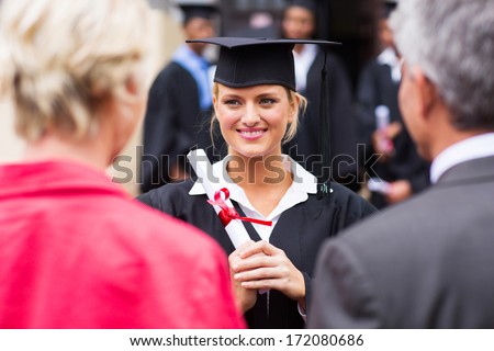 middle aged couple attending daughter\'s university graduation ceremony