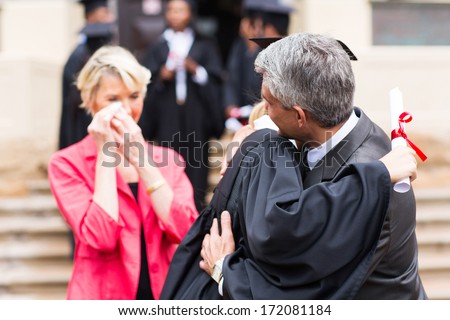 middle aged father hugging daughter at graduation ceremony