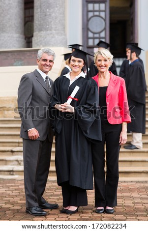 portrait of young girl graduate standing with parents at graduation ceremony