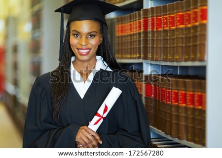 pretty african american college student wearing graduation attire in library