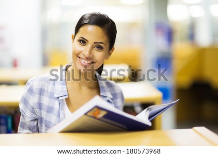 attractive female college student with a book in library attractive female college student with a book in library