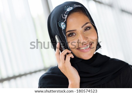 cheerful modern muslim woman talking on cell phone