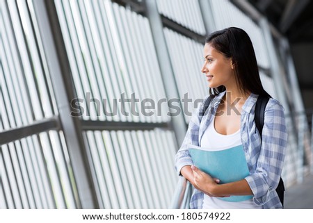 thoughtful female student on campus looking outside window