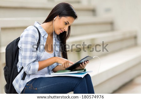 female university student using tablet computer listening music on campus