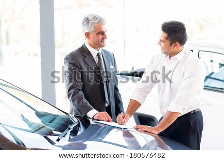 senior car salesman just made a sale to young customer