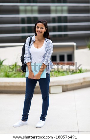pretty college student outside school building holding book