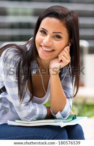 happy female student listening to music on campus