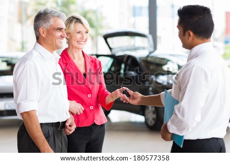 senior couple receiving car key after buying a new car