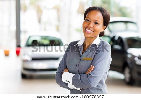 pretty african vehicle saleswoman with arms crossed in showroom