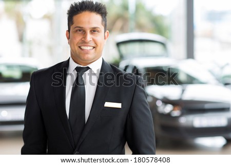 happy young indian car salesman in showroom