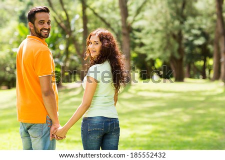 cute indian couple holding hands and looking back outdoors
