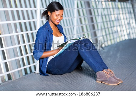 pretty young african uni student reading a book