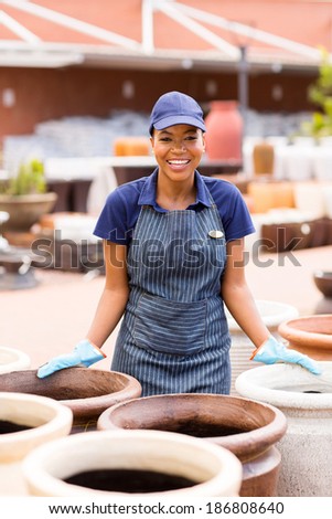 cheerful african american female worker at garden center selling clay pots