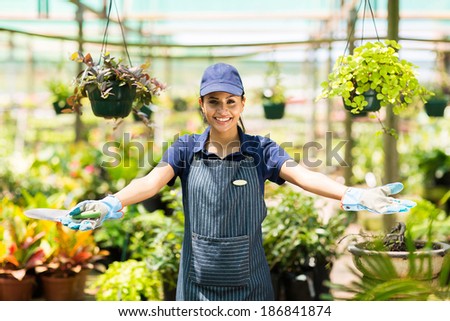 happy female florist portrait in greenhouse with welcome gesture