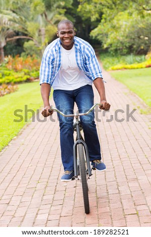 happy african american man riding bicycle outdoors