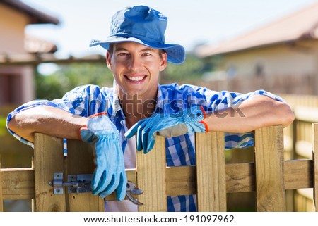 young man resting by garden fence after doing some work in the yard