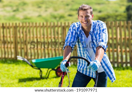 happy man mowing lawn at home garden